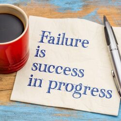 Failure is success in progress - handwriting on a napkin with a cup of coffee