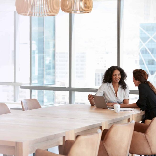 Two Businesswomen Using Laptop In Boardroom Meeting